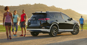 Four young students standing around a Toyota Rav4 in the hills