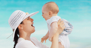 Mother playing with her infant by the water