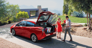 Young couple loading a vase of flowers into the trunk of a red Toyota Prius