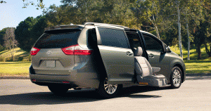 A greenish beige Toyota Sienna with a handicap accessible middle seat extending out the door 