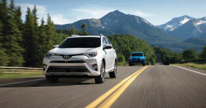 A white and a blue Toyota Rav4 driving on the highway through the mountains